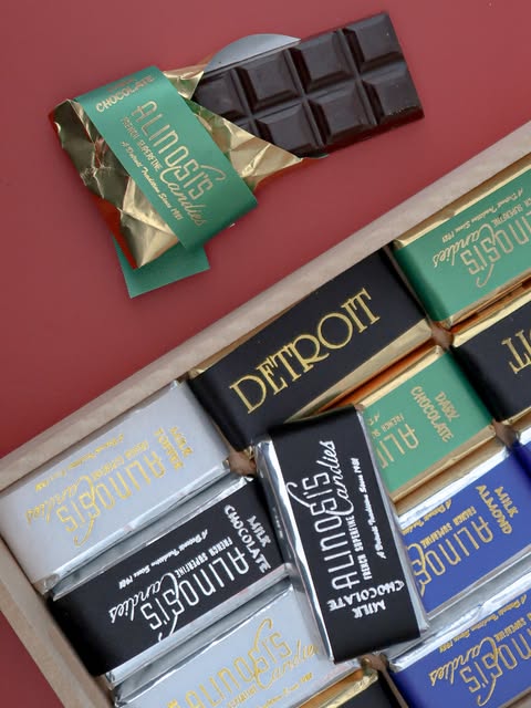 Unwrapped Alinosi chocolate bars in gold, green and black packaging